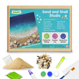 Kidoart Sand and Shell Studio craft kit shown with its printed box on a white background, plus included materials arranged below: sand, shells, paintbrush, glue, paint pots, and colorful pigment blocks. The box features a beach scene and lists contents such as paint brush, 7x7 canvas, paint glue, paint brush, white glue, magic clay, and ceramic powder.